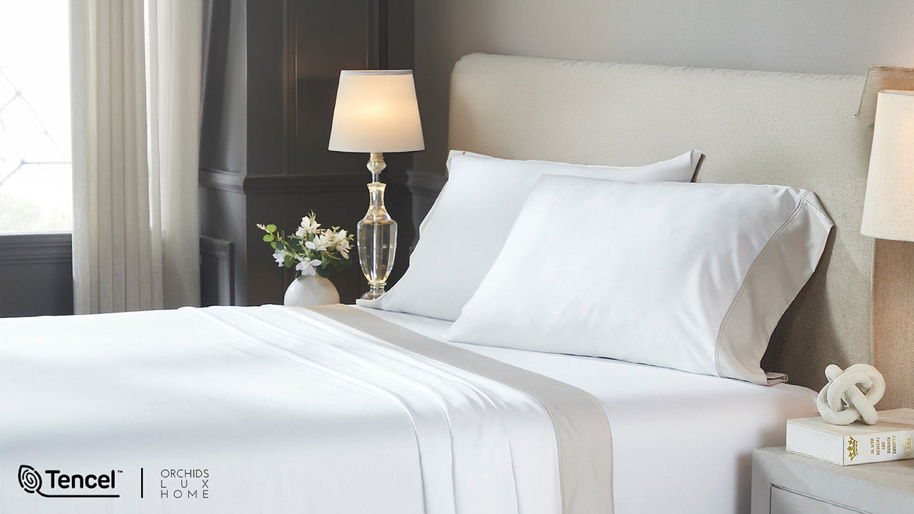 Bright, minimalist bedroom with a neatly made bed dressed in crisp white sheets and pillows. Close-up highlights smooth Tencel™ bedding, conveying a clean, soft, hotel-style feel.