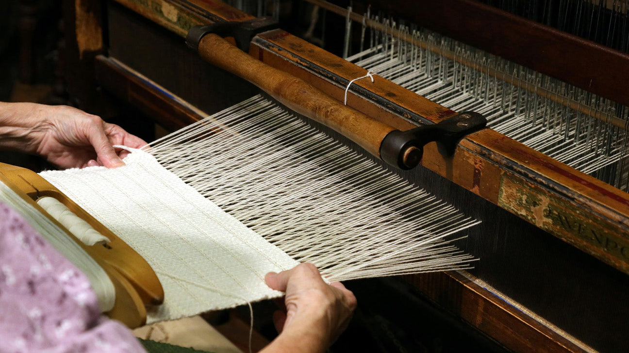 Hand weaving premium cotton fabric on a traditional loom showcasing the craftsmanship behind luxury bedding.