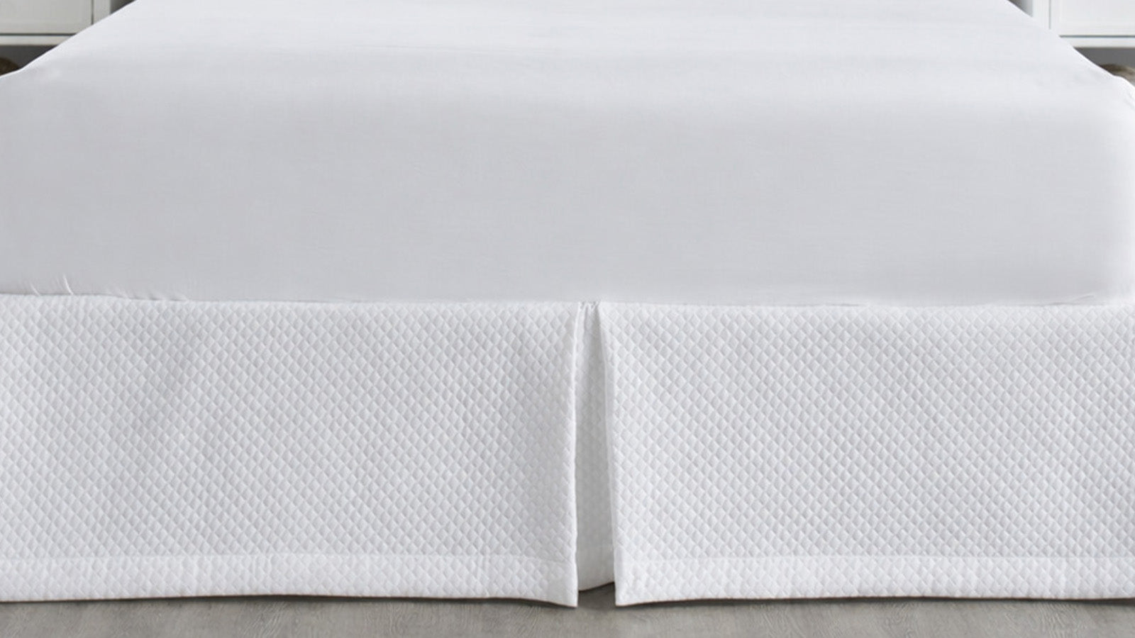 White quilted bed skirt with a tailored center pleat adding a clean, elegant finish to a luxury bed.