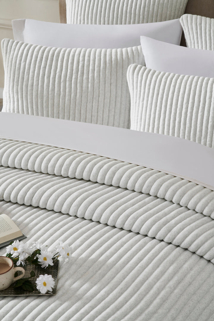 QT-374-9496_4|Serene light grey ribbed quilt and soft pillow shams on a bed, offering elegant textured comfort for a tranquil space.