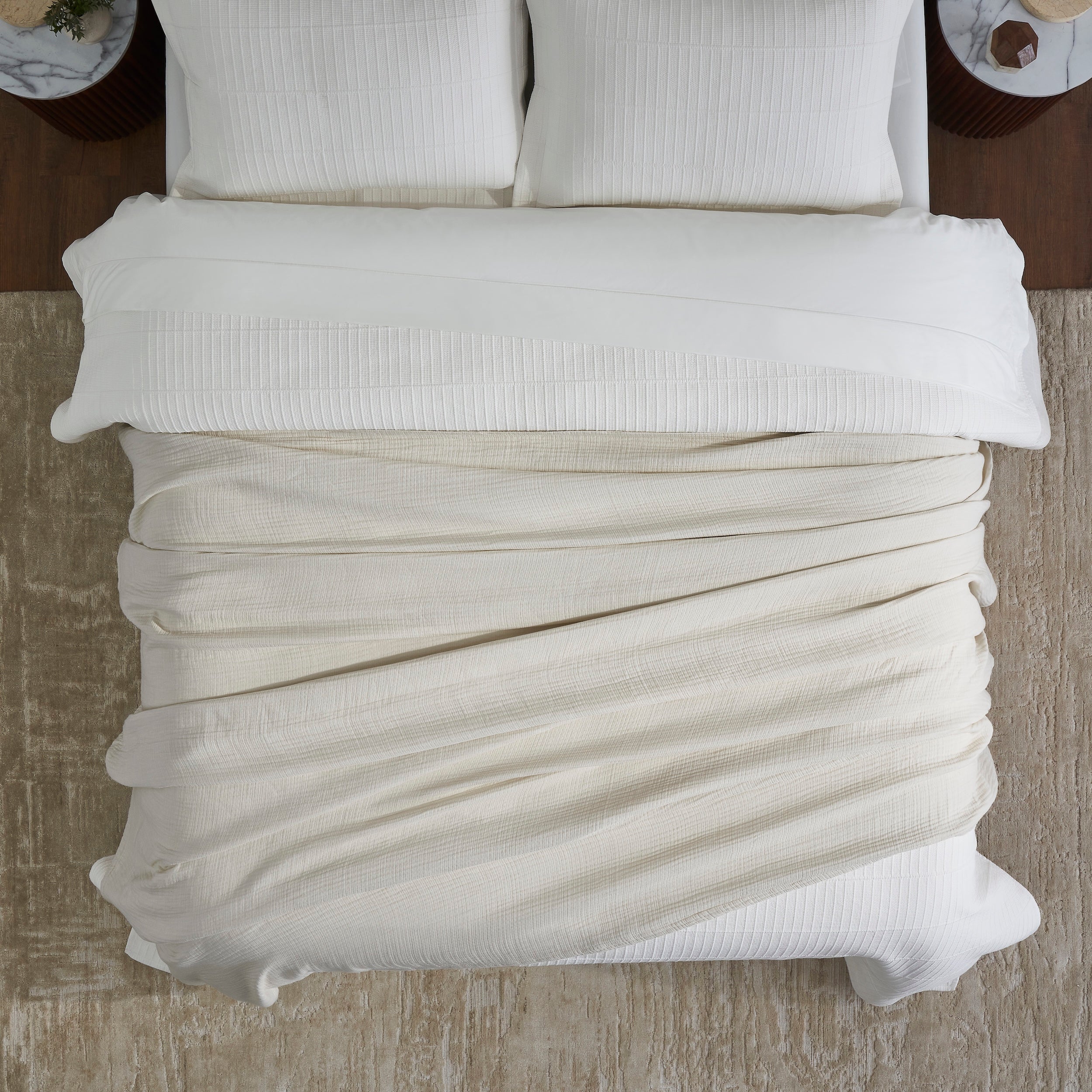 BL-862-9496_4|Overhead view of a light beige cotton blanket folded neatly on a bed, showcasing its soft texture and cozy appeal.