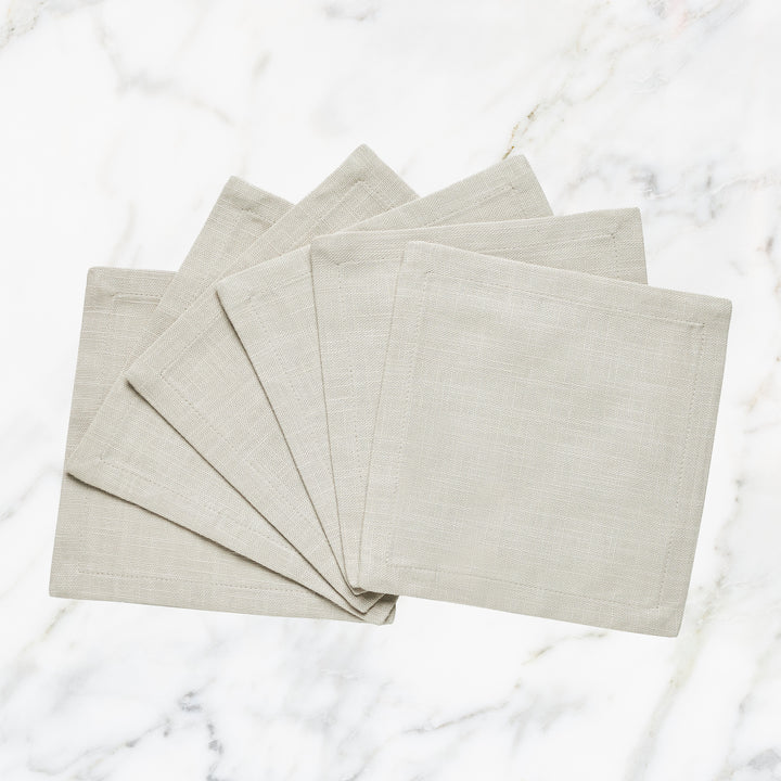 CNP-4912-66_1|Set of fan-folded natural beige linen dinner napkins on marble, ideal for elegant and reusable neutral table settings.