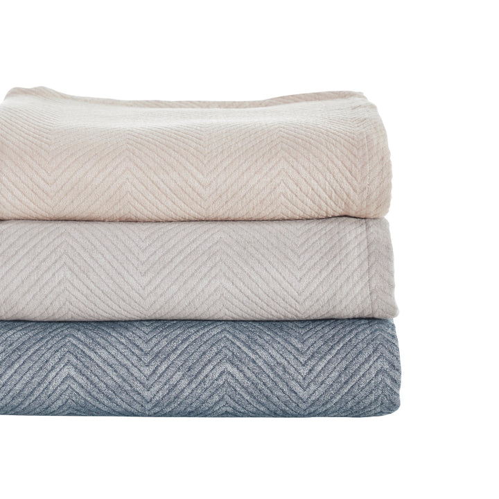BT-123-11096_3|Stack of three chevron throw blankets: light beige, pale gray, and blue. Stylish, textured blankets for versatile decor.