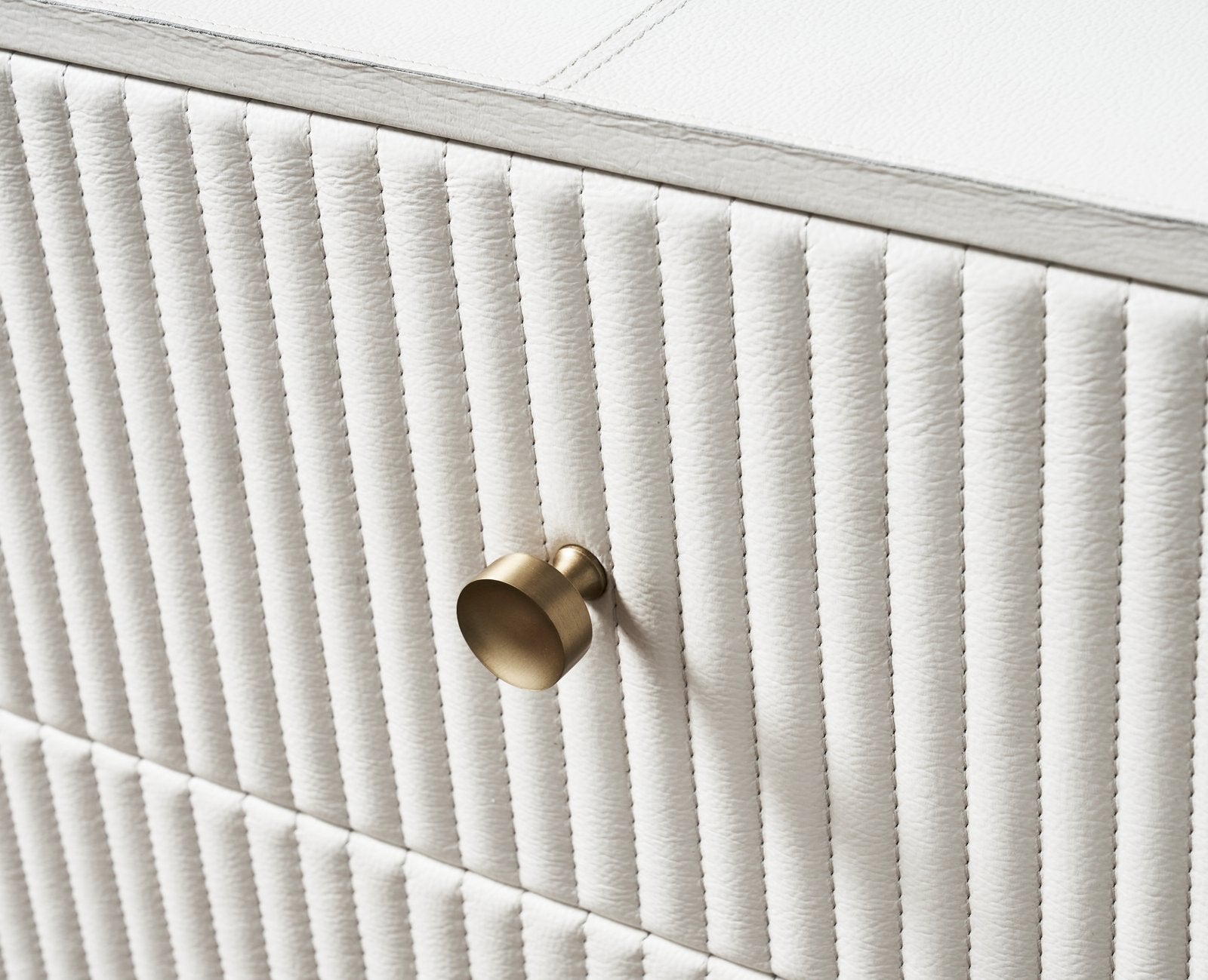 FN-5203-642033_3|Close-up of a sophisticated white dresser with textured vertical channel detailing and a chic brass round knob handle.