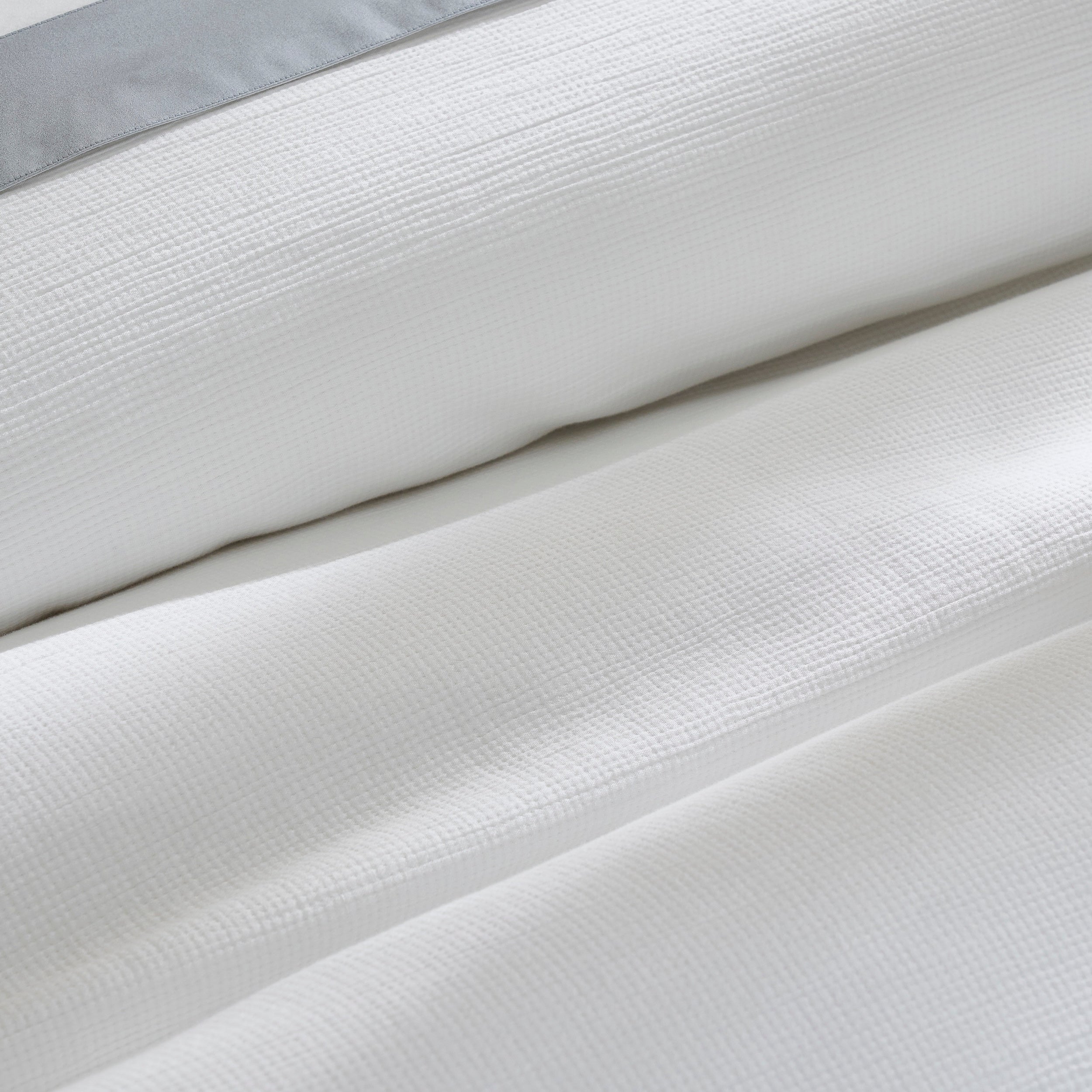 DT-067-10692_7|Folded white textured duvet cover with elegant grey stripe detail, showcasing premium cotton for ultimate bedroom comfort.
