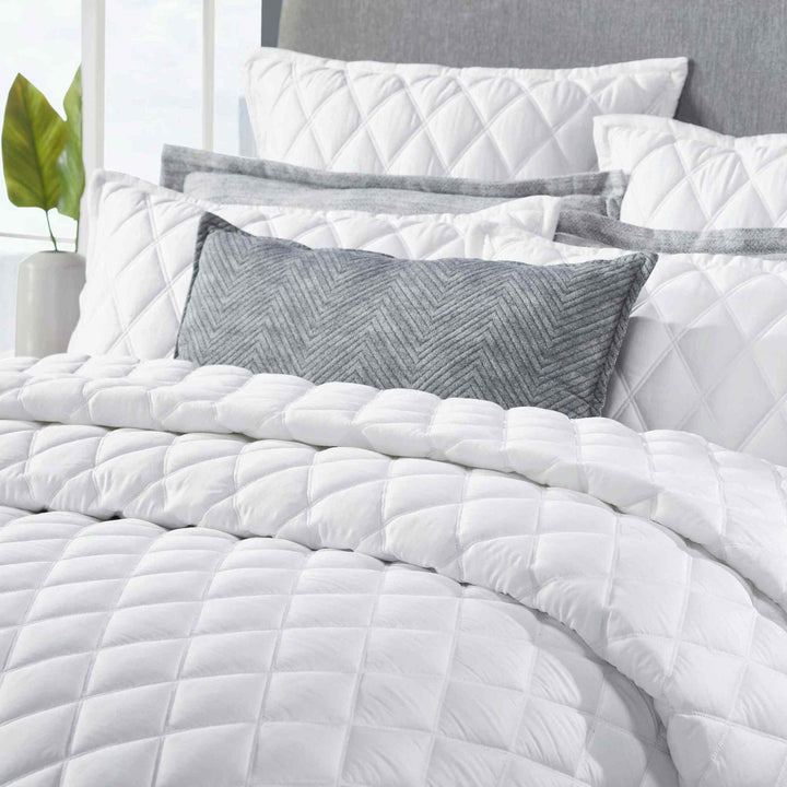 CL-179-9496_3|Close-up of white diamond-quilted coverlet and pillows, highlighting soft texture and intricate stitching detail.