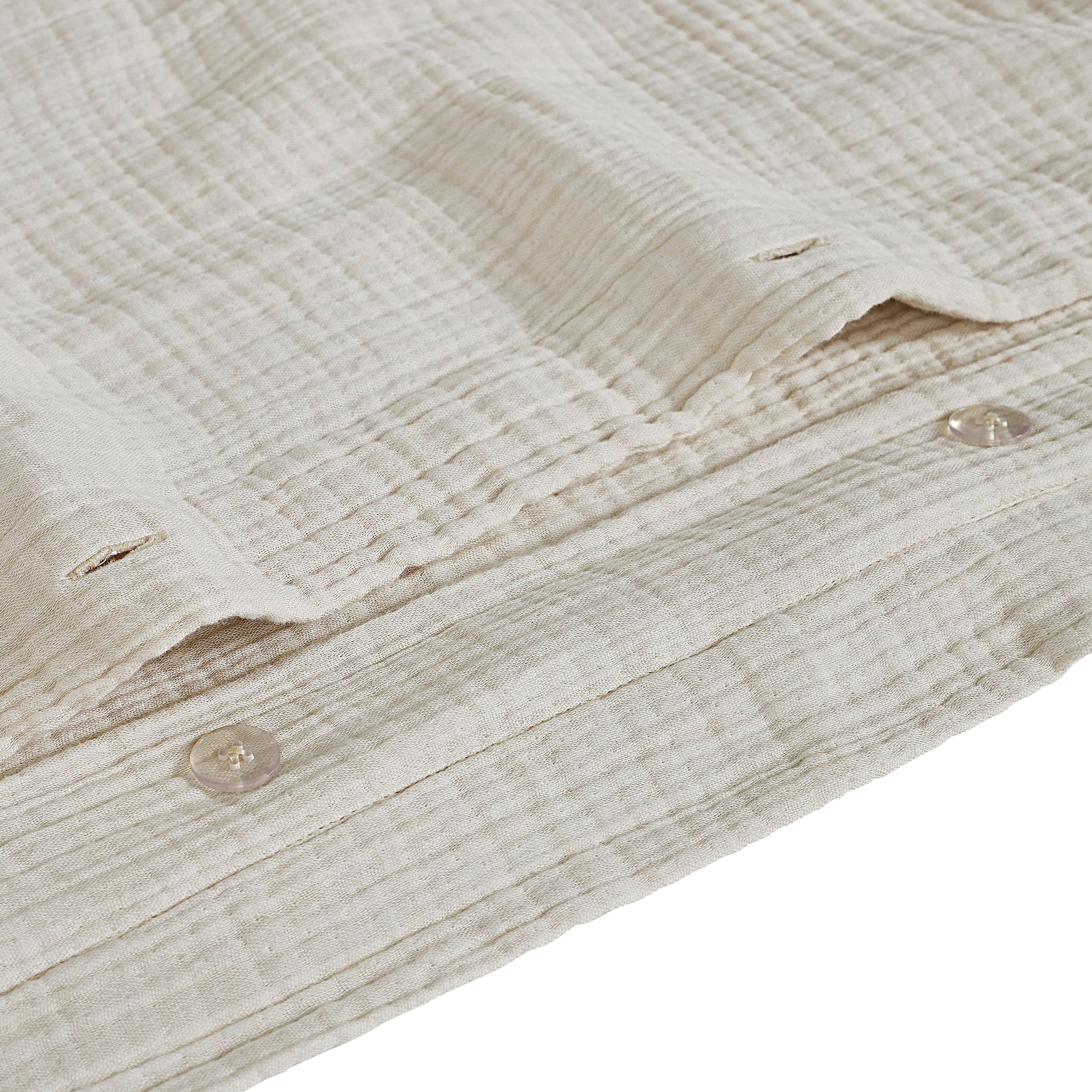 DT-049-10692_8|Close-up of the subtle button closure detail on a light cream textured organic cotton gauze duvet cover, high quality.