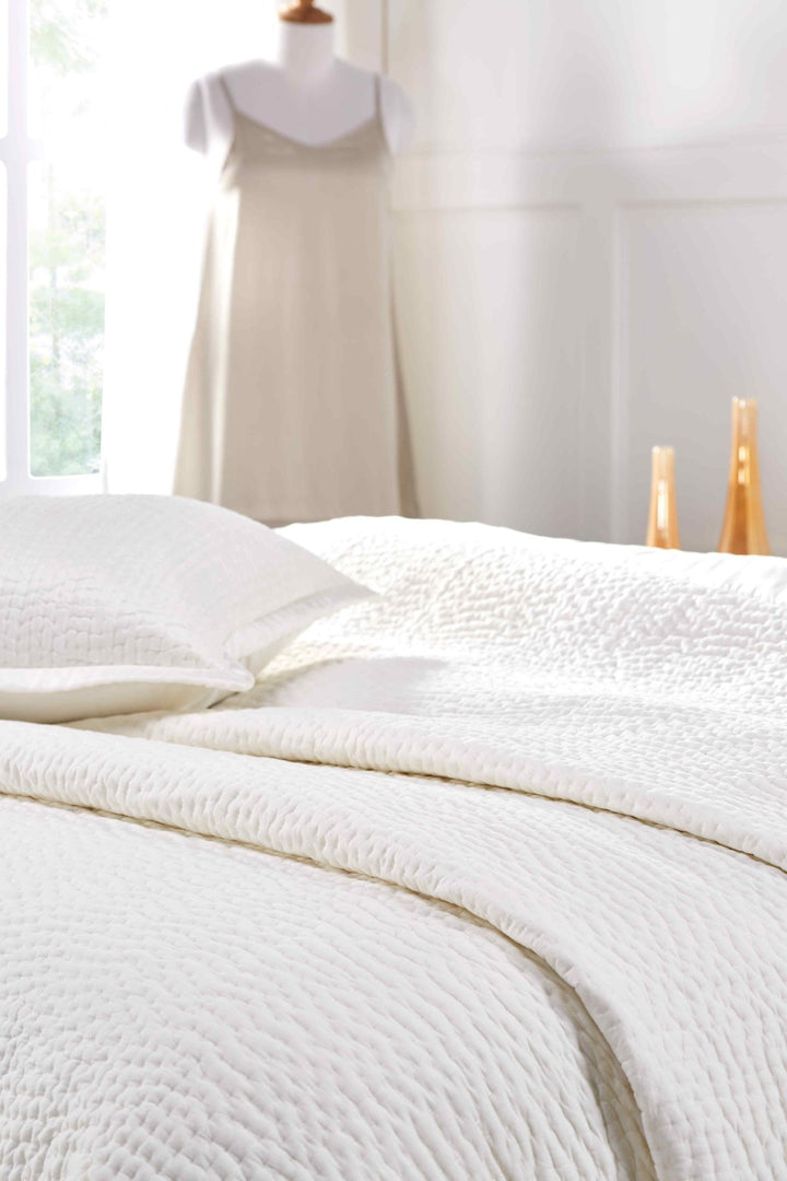 CL-165-11096_4|Close-up of a pristine white coverlet on a bed, highlighting its plush, subtle textured pattern and luxurious feel.