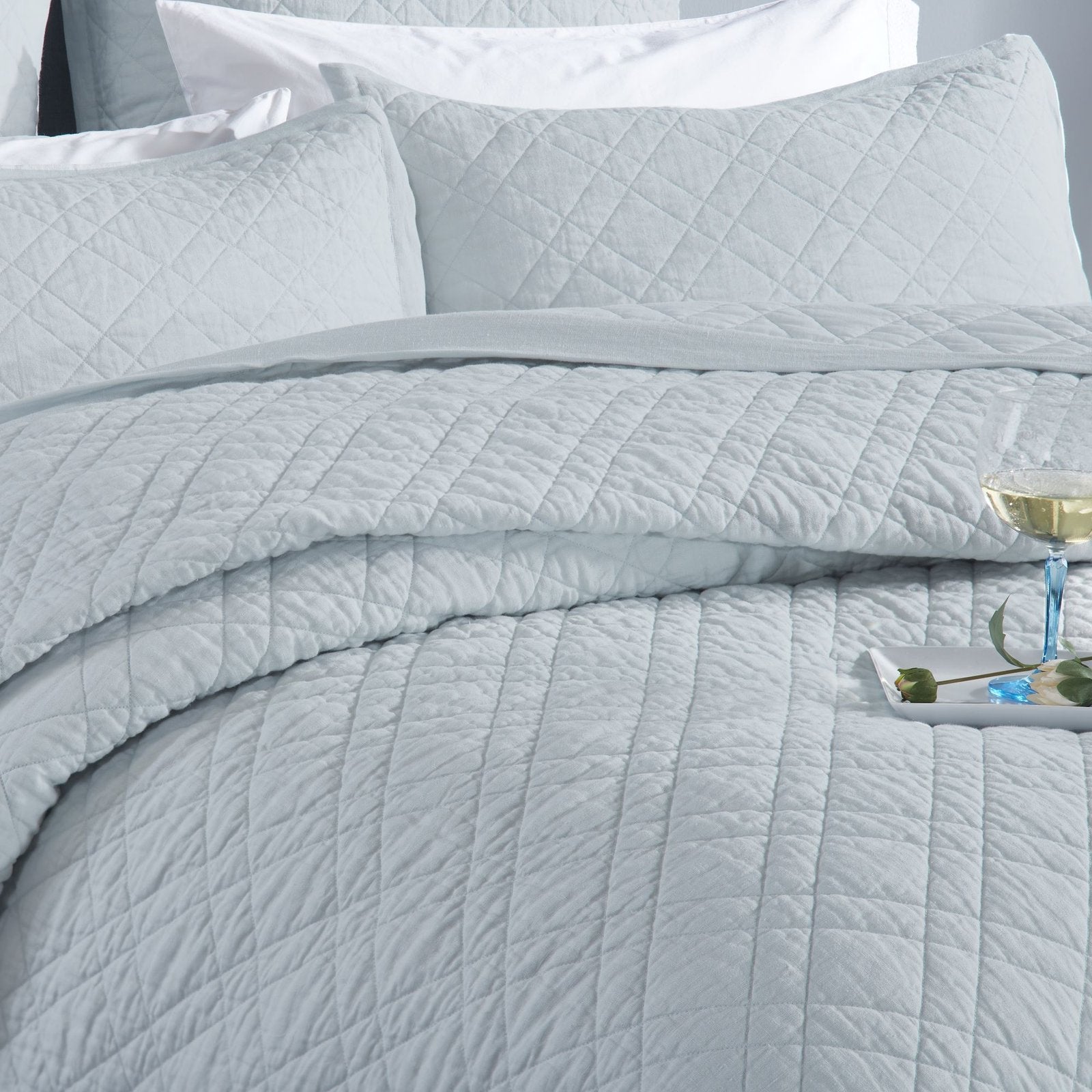 CL-255-9496_4|Elegant light blue quilted coverlet on a bed with matching pillows and a drink. Creates a serene and luxurious retreat.