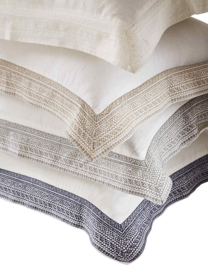 ES-016-2626_1|Stacked white, cream, and grey linen duvet covers, elegant embroidered border detail for stylish bedding set.