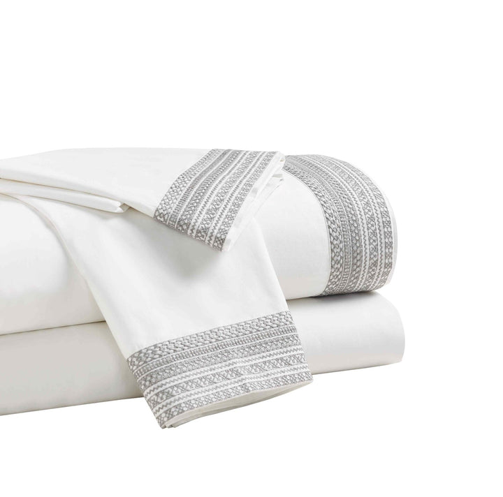QSS-502-6080_2|Stack of neatly folded white 100% cotton sheets with elegant decorative trim, highlighting quality and softness.