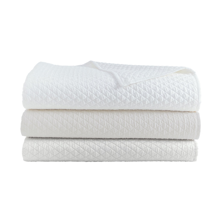 CL-266-9496_7|Stack of three diamond quilted coverlets in white, ivory, and light grey, offering versatile and elegant bedroom bedding.
