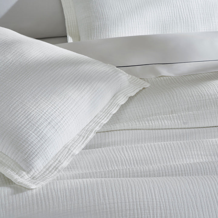 SS-048-2026_3|Elegant white organic cotton duvet cover and matching pillow shams draped gracefully on a bed, minimalist style.