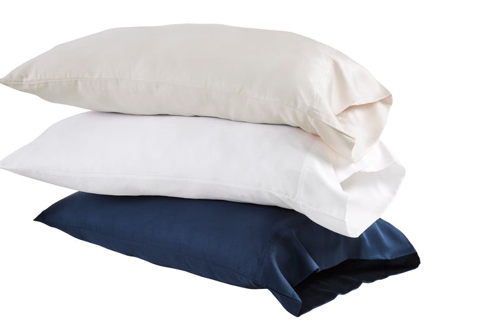 ASP-509-X_1|Stack of three 100% Lyocell pillowcases: pale beige, white, and navy. Each features a smooth sateen weave.