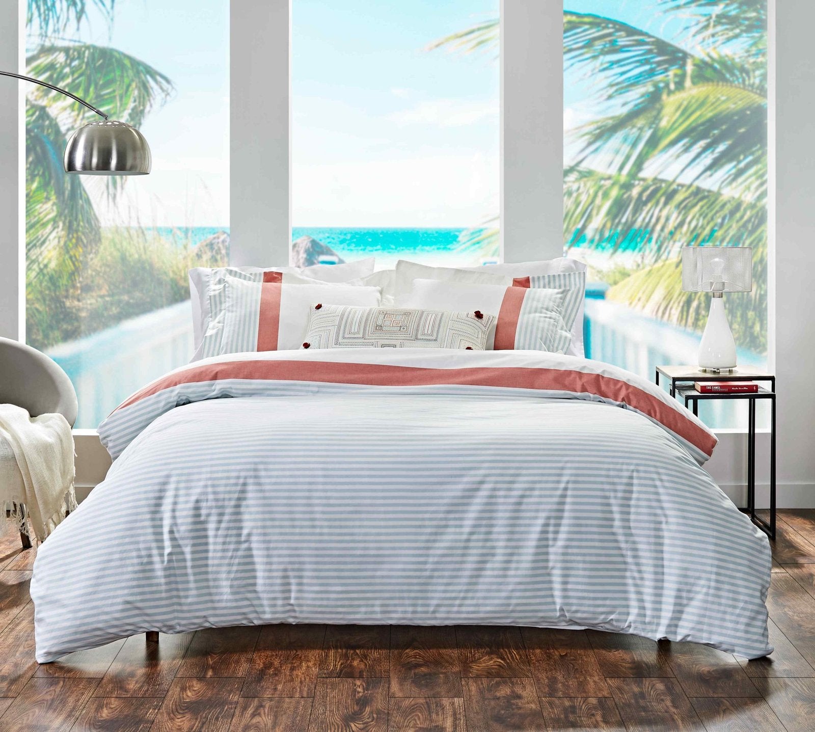 DT-001B-6588_1|Coastal bedroom setting with light blue and white striped duvet, featuring coral accent and decorative pillows.