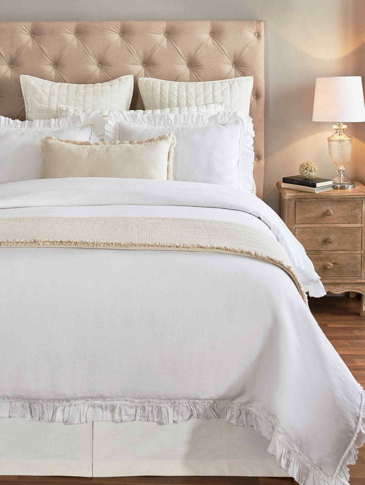 DT-017-X_1|Fresh white ruffled duvet cover set on a tufted queen bed, featuring matching shams and a textured throw blanket.