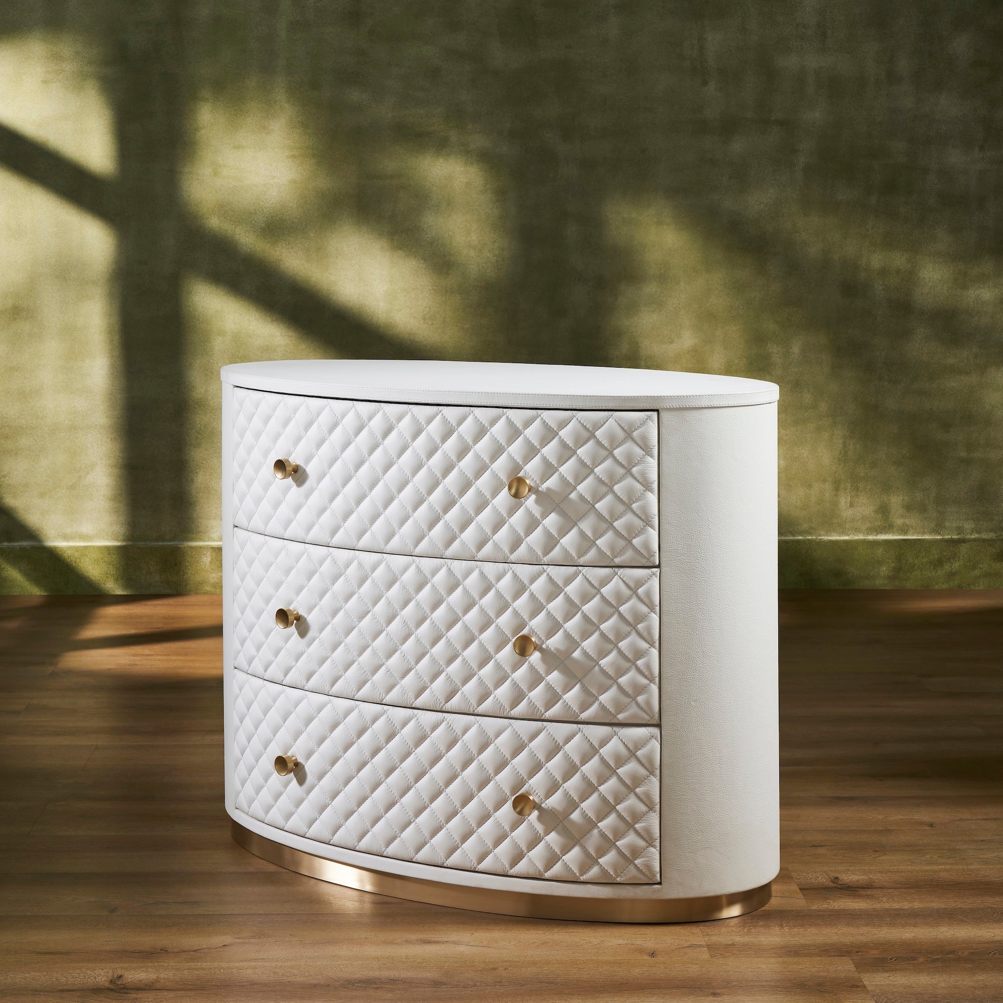 FN-5218-482036_2|Elegant white leather oval chest of drawers, featuring a chic quilted design, radiant gold hardware, and a sleek gold base.