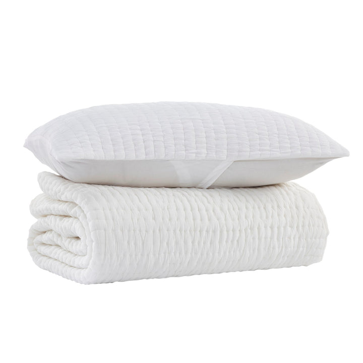 QT-359-9496-LOT1_7|Stacked white textured quilt and matching pillow sham for a cozy bedroom, featuring soft, inviting fabric and modern design.