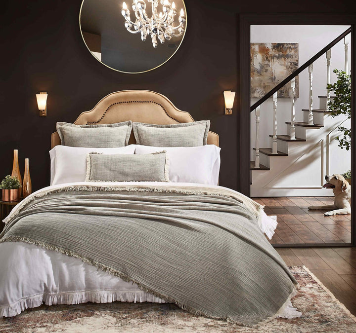 BT-113-11096_5|Beige upholstered bed, sage green fringed throw blanket, white ruffled bedding, accent pillows, wall sconces.