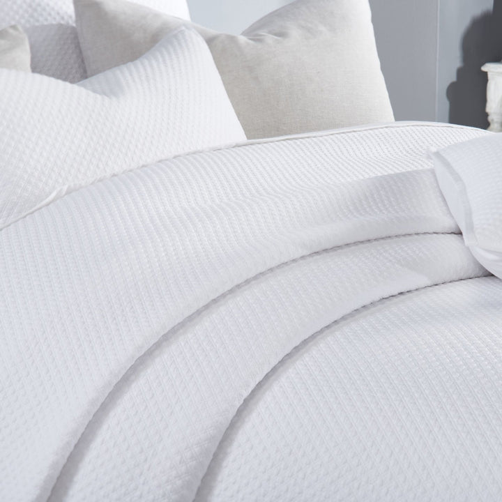 CL-200-9496_4|Detailed view of the pristine white quilted coverlet, highlighting its exquisite diamond pattern and soft fabric.