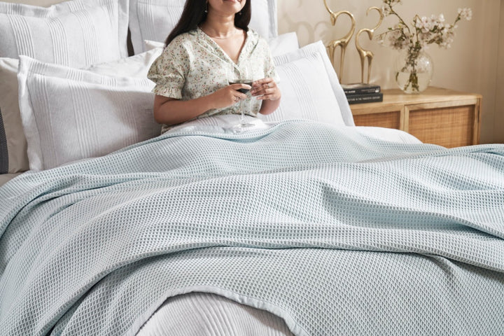 BL-857-11096_5|Woman relaxing in bed, covered by a light blue waffle knit blanket, for ultimate cozy comfort. (111)