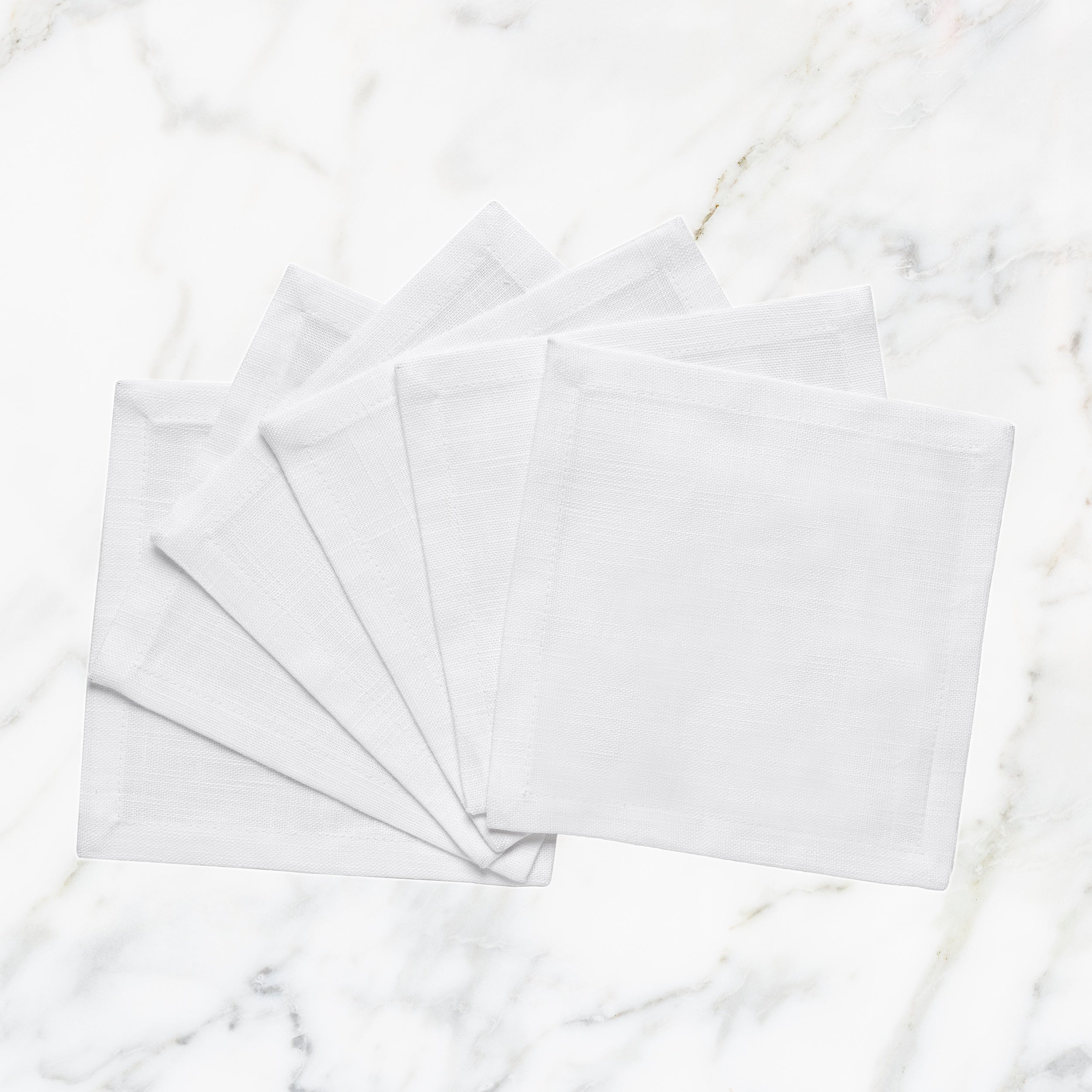 CNP-4909-66_1|Set of fanned white linen napkins displayed on a pristine white marble background for elegant table settings.