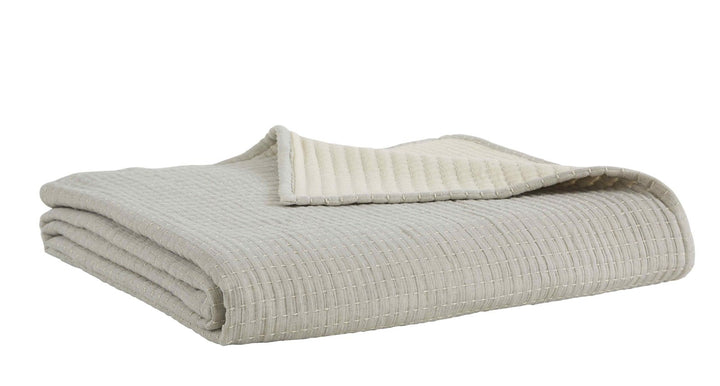 BT-107-9496_3|Cream textured reversible quilt blanket, folded neatly, showcasing soft cream reverse for cozy bed and neutral home decor.