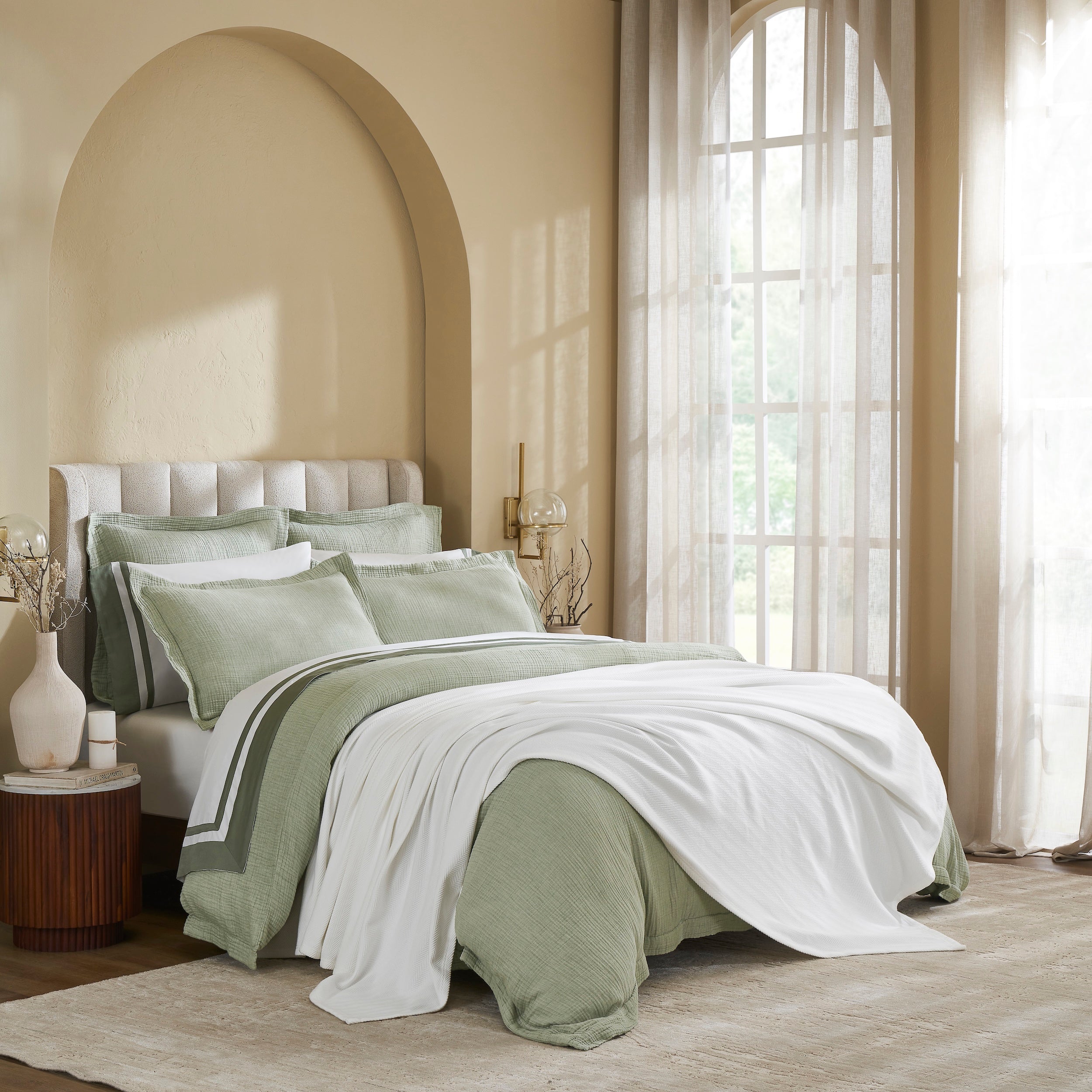 BL-865-9496_3|Soft white woven blanket elegantly draped over a sage green duvet, perfect for layering and enhancing a chic bedroom aesthetic.
