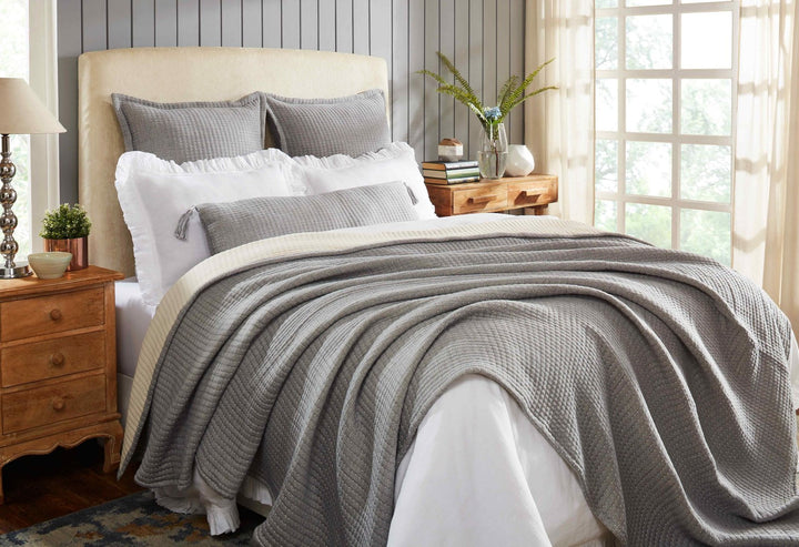 BT-108-11096_4|Stylish grey textured reversible quilt blanket elegantly draped over a bed with white sheets, enhancing modern bedroom decor.