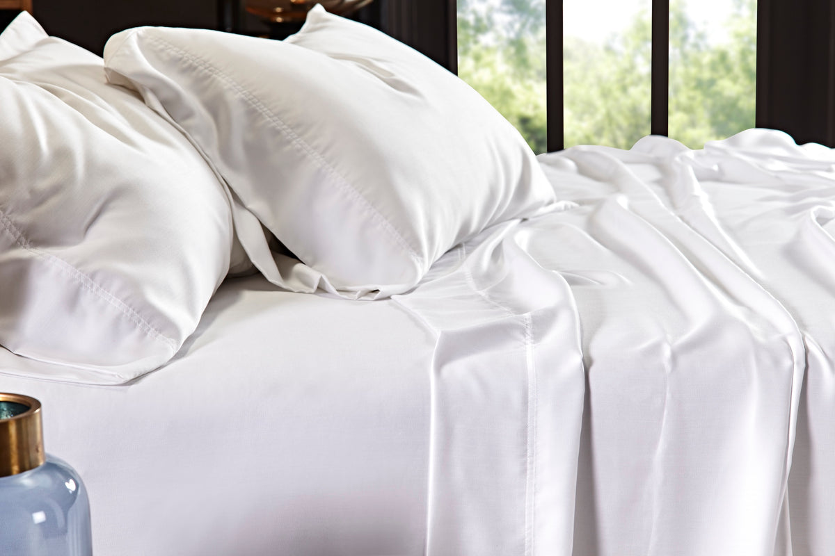 KFL-509-7880_3|Close-up of white 100% Lyocell sheet set on a bed, showcasing pillowcases with stitched borders and a draped flat sheet.