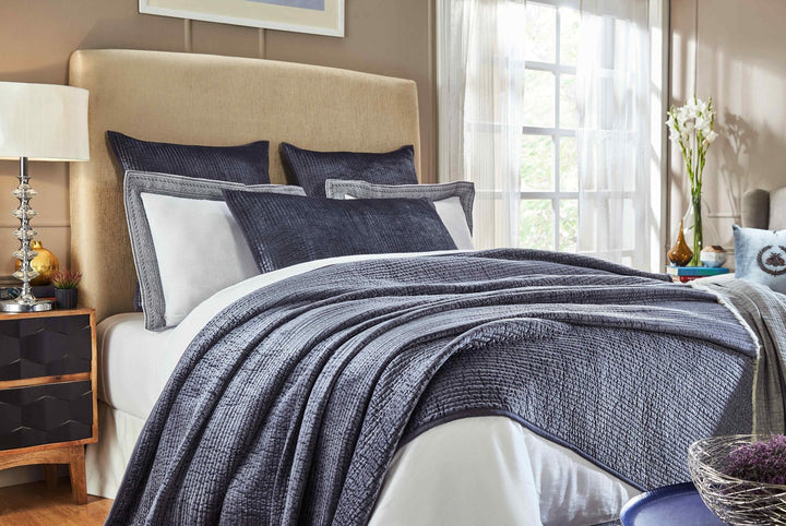 CL-159-9496_2|Dark blue quilted coverlet with a textured, ribbed pattern on a bed in a bright bedroom. Modern luxurious bedding.