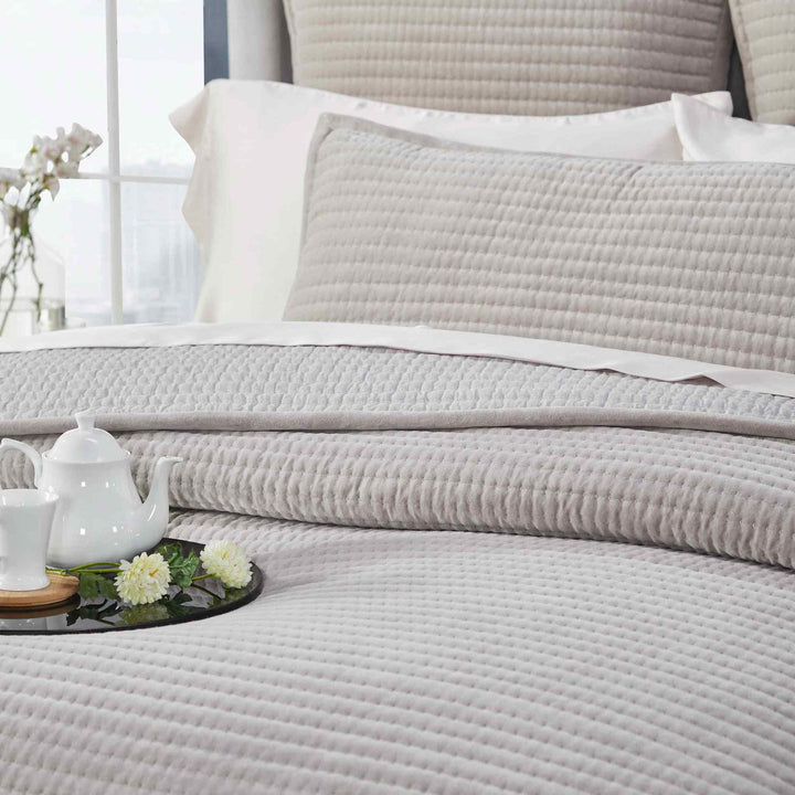 CL-188-11096_6|Detail view of a soft grey quilted coverlet on a bed, highlighting its subtle channel texture and comfort.