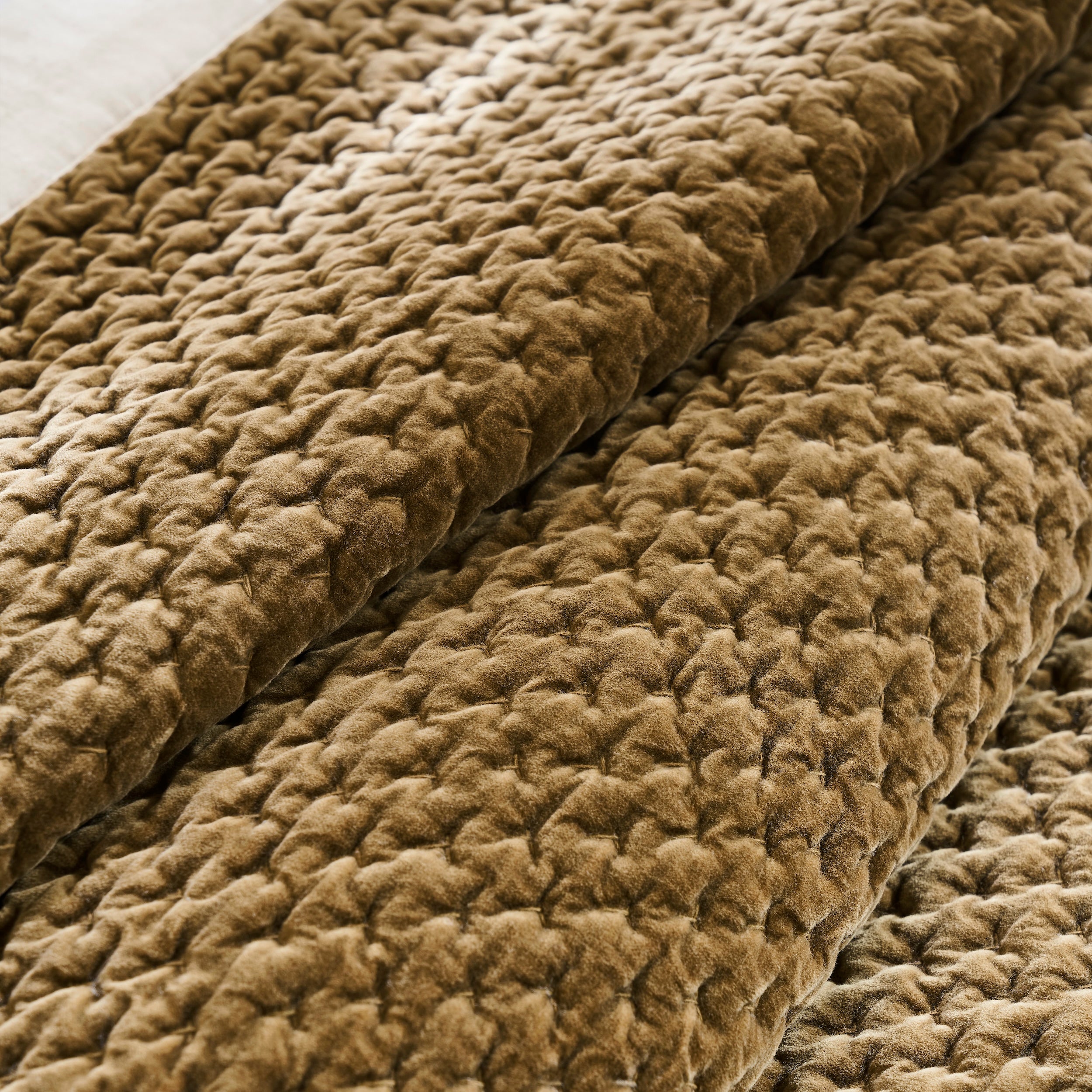 QT-378-9496_7|Close-up of richly textured, folded golden brown quilted velvet bedspread, showcasing its soft, cozy, and luxurious feel.