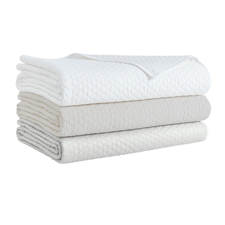 CL-266-9496_8|Stack of three diamond quilted coverlets in white, ivory, and light grey, perfect for layering luxurious bedroom bedding.