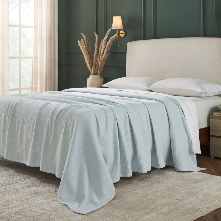 BL-863-9496_2|Soft light blue muslin gauze blanket providing a cozy, breathable layer for comfortable sleep in a modern bedroom setting.