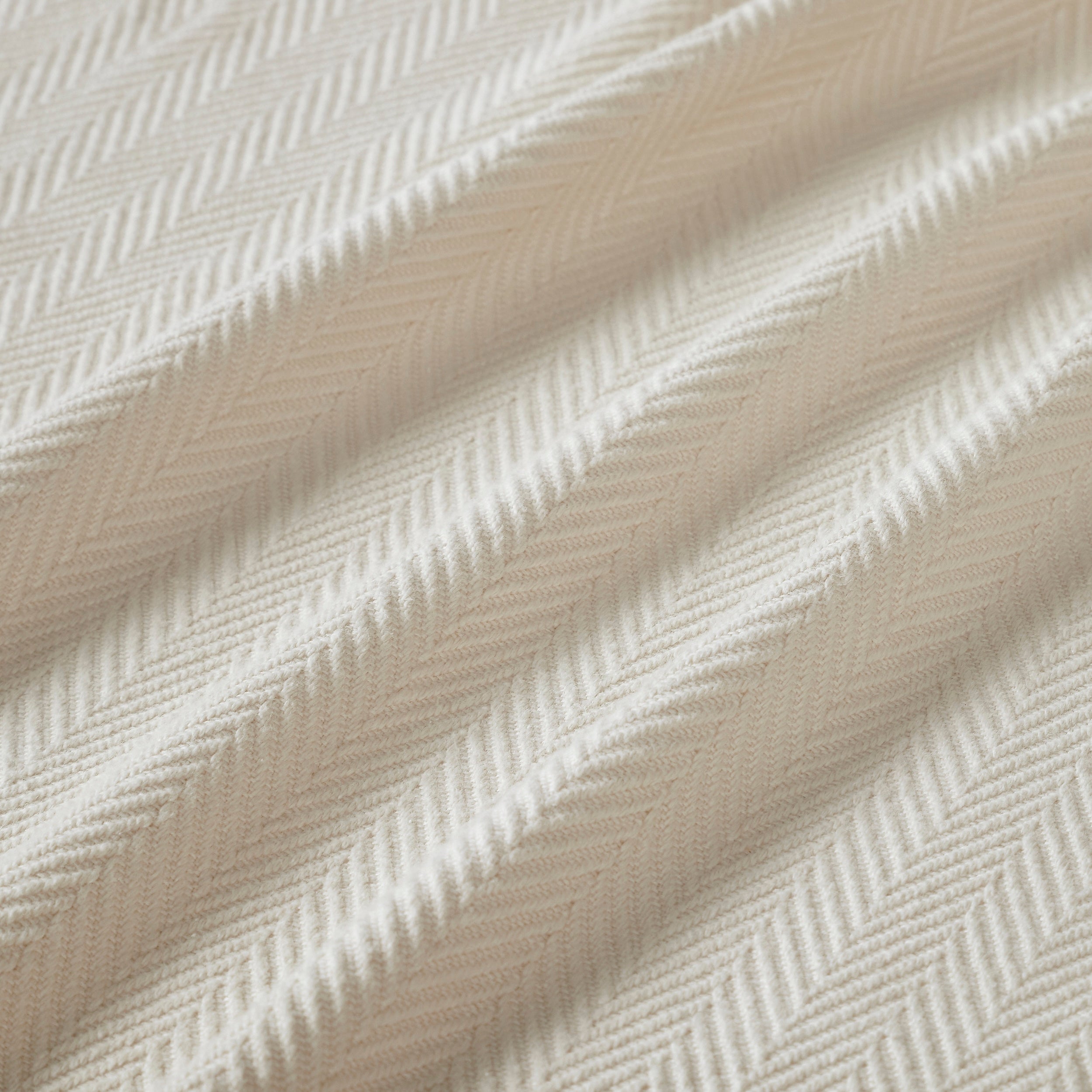 BL-866-9496_9|Close-up of luxurious light beige blanket with a detailed herringbone weave texture, highlighting its soft fabric and pattern.