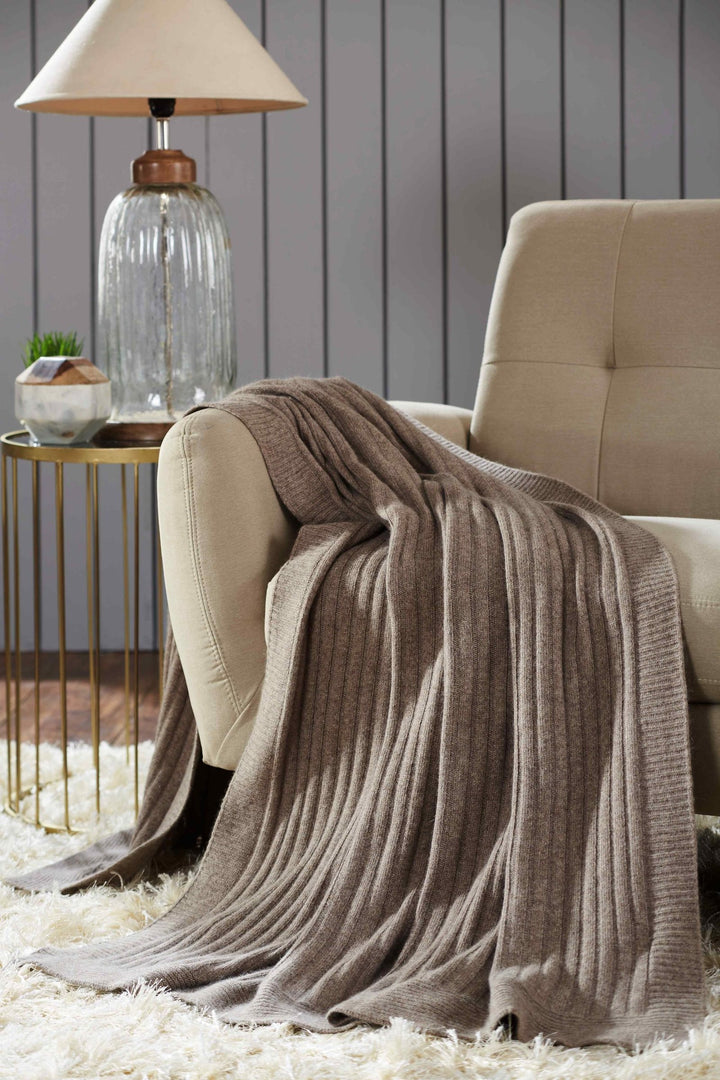 TW-901B-5070_1|Luxurious ribbed brown knit throw blanket draped over a beige armchair, providing warmth and a cozy aesthetic.
