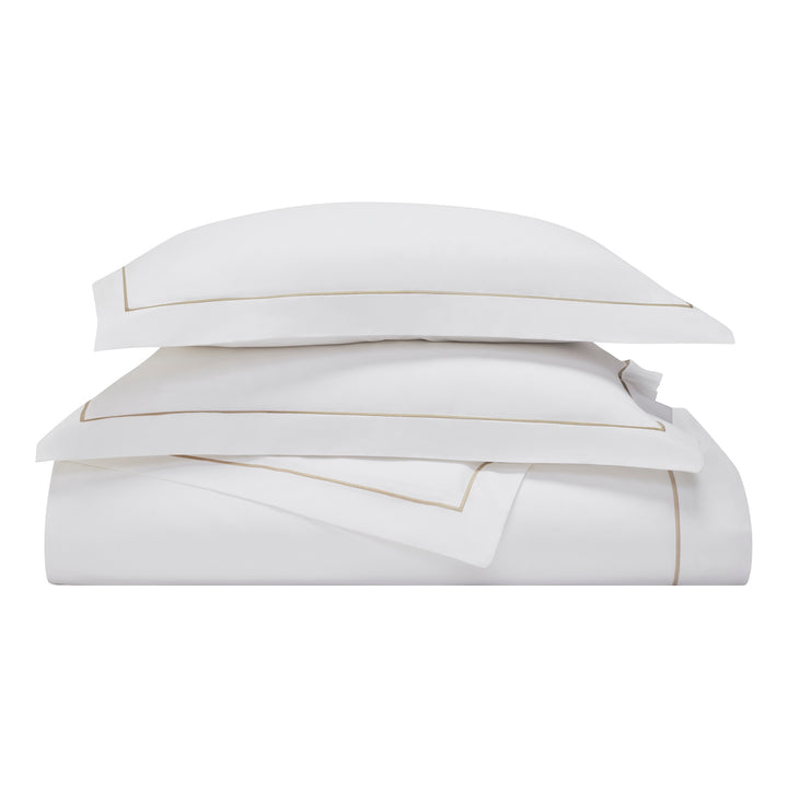 DT-056-9092_4|Stacked luxurious white duvet cover and pillow shams with elegant golden trim. Premium quality bedding product shot.