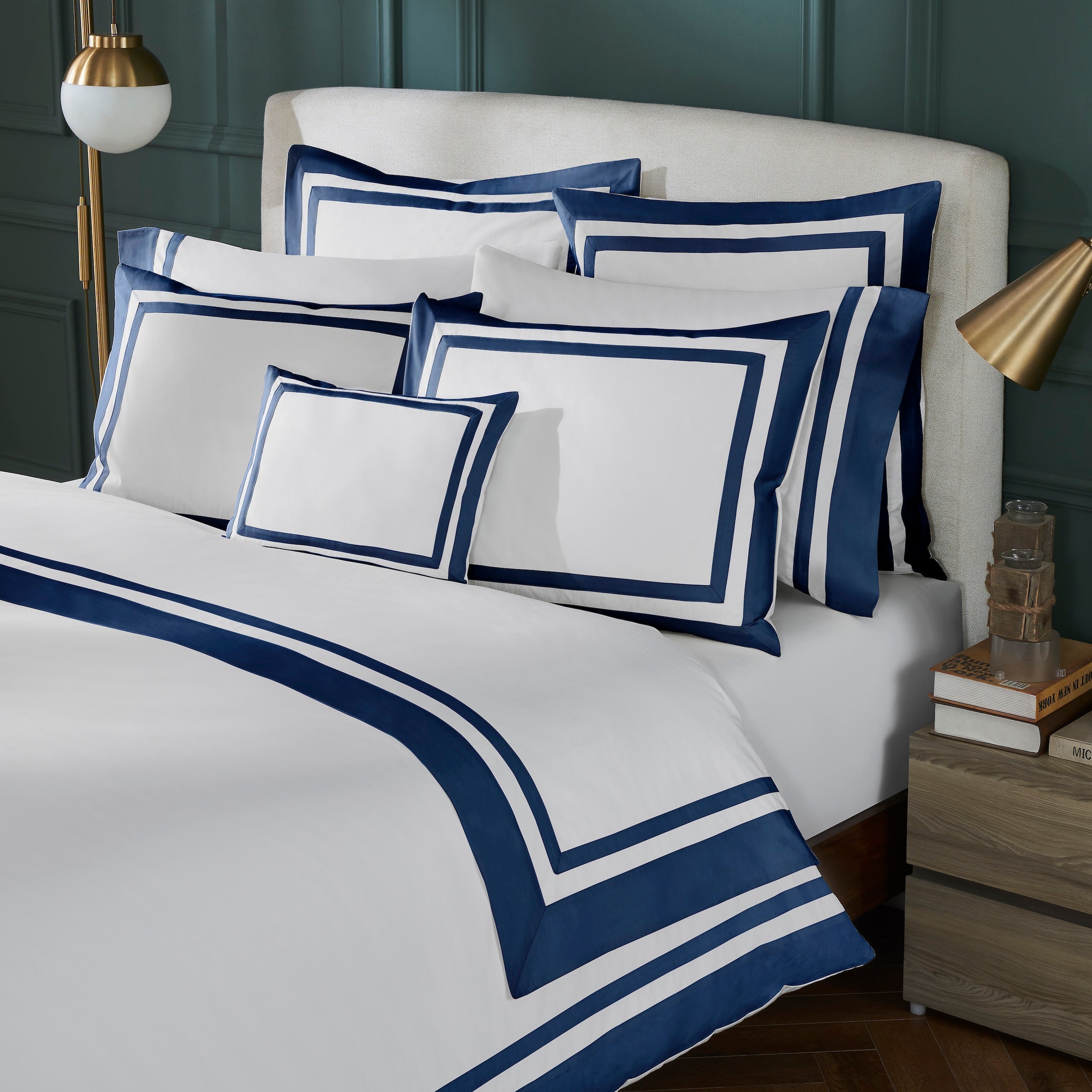 DT-069-9092_2|A luxurious white duvet cover with elegant navy blue borders and multiple pillow shams on a classic bed setting.