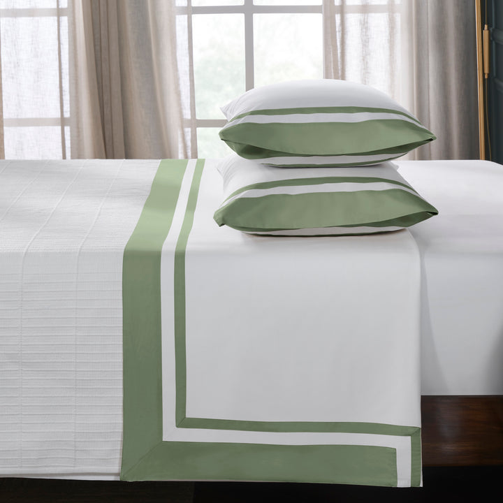 QFL-542-6080_3|Inviting bed with luxurious 100% cotton sheets, crisp white with elegant green borders and stacked pillowcases.