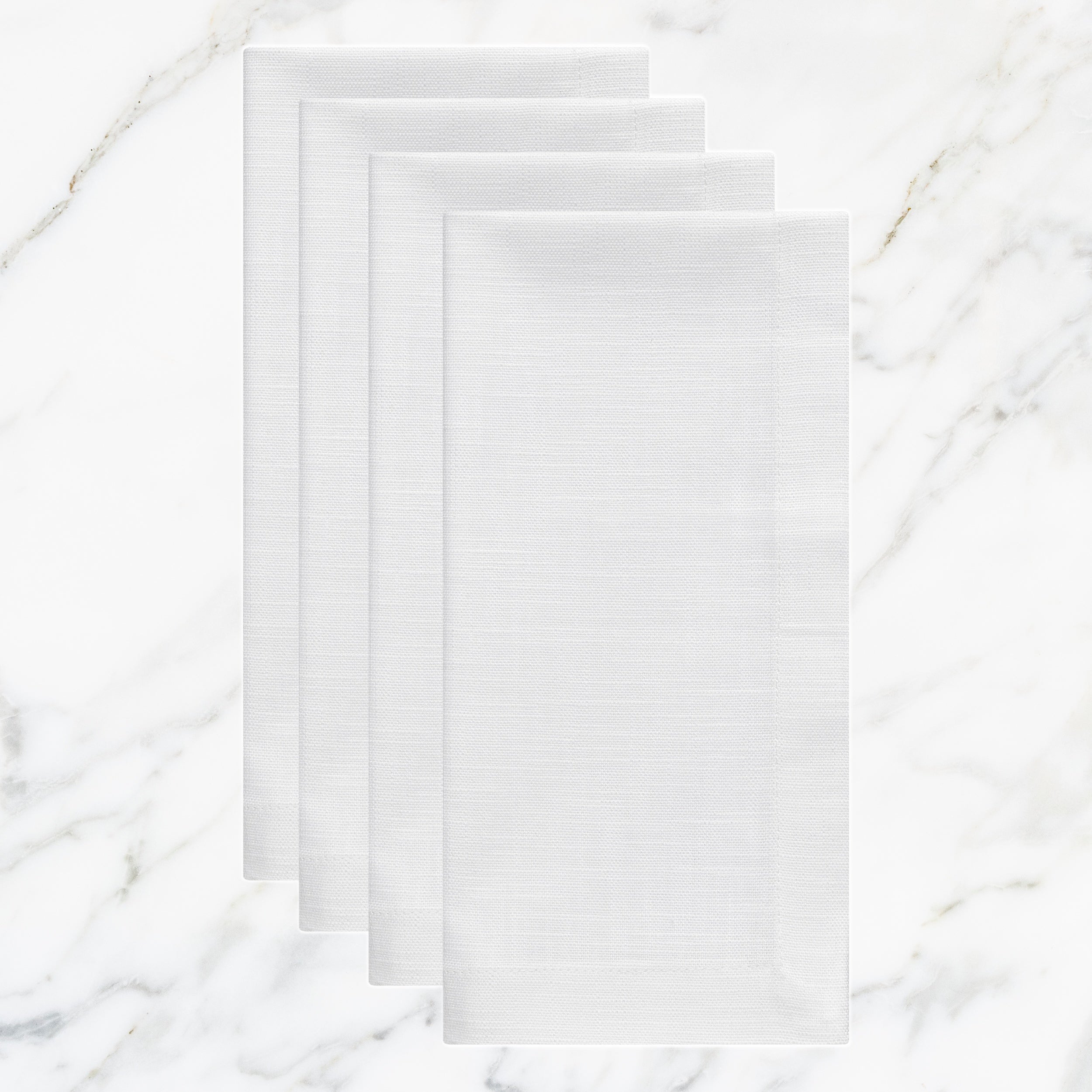 NP-4809-2020_1|Set of four crisp white linen-look fabric dinner napkins, folded on a sophisticated white marble surface.