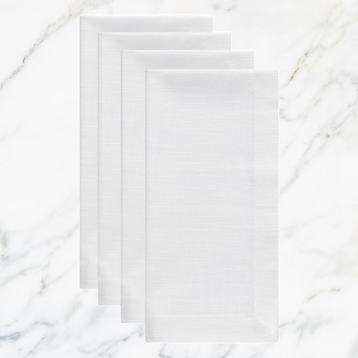 NP-4809-2020_1|Set of four crisp white linen-look fabric dinner napkins, folded on a sophisticated white marble surface.