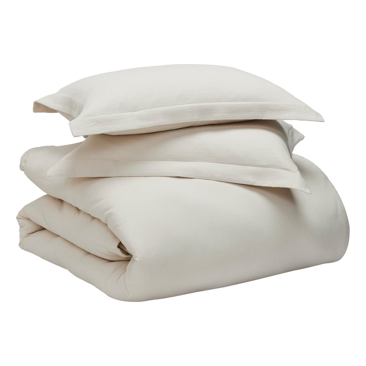 DT-068-10692_9|Stacked light beige textured duvet cover with two matching shams, creating a complete and elegant bedding set for cozy bedrooms.