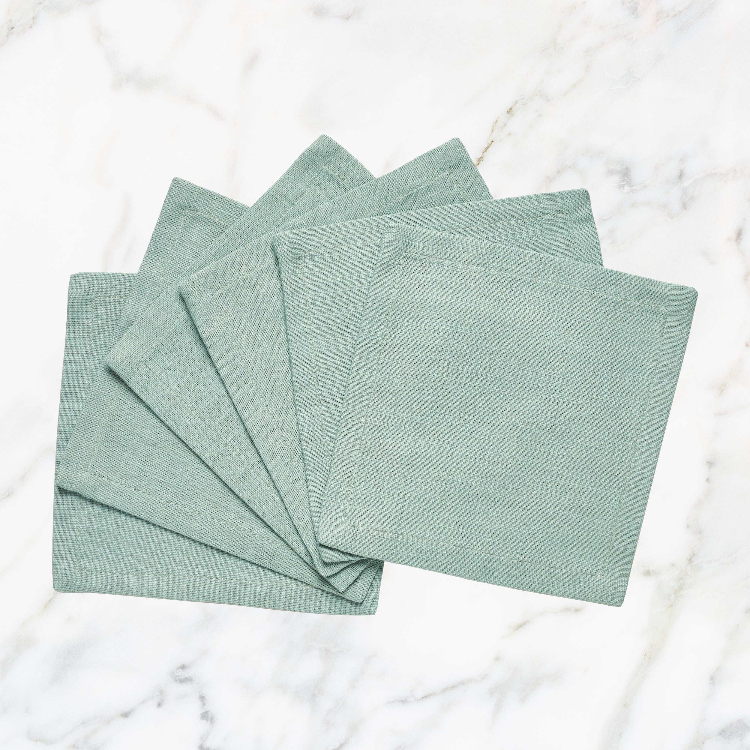CNP-4911-66_1|Set of fan-folded mint green linen dinner napkins on marble, perfect for stylish dining, reusable, modern table decor.