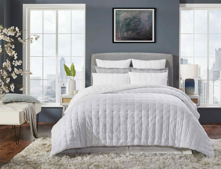 QT-353-9496_1|Modern white quilted bedding set on a king-size bed in a stylish bedroom with large windows overlooking a city skyline.