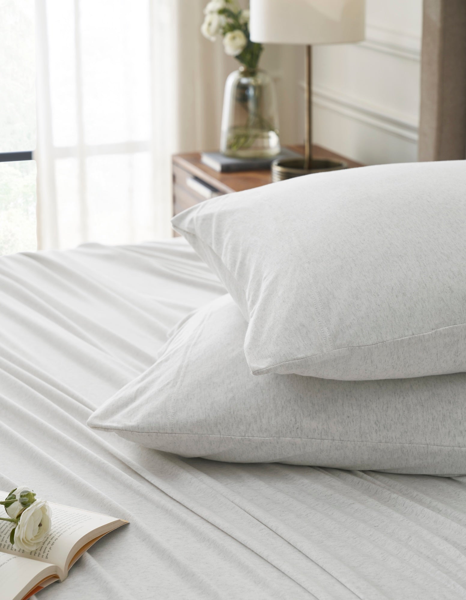 QSS-525-6080_4|Stack of white 100% cotton jersey pillowcases on bed, showcasing the soft and comfortable fabric texture.