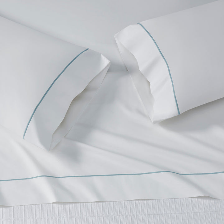 TFL-530-3980_4|Top-down view of a pristine white 100% cotton sheet set with delicate light blue piping, perfect for luxury bedding.