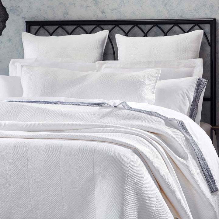 CL-170-11096_3|Close-up of elegant white chevron woven coverlet on a plush bed, showcasing its textured pattern and sophisticated design.
