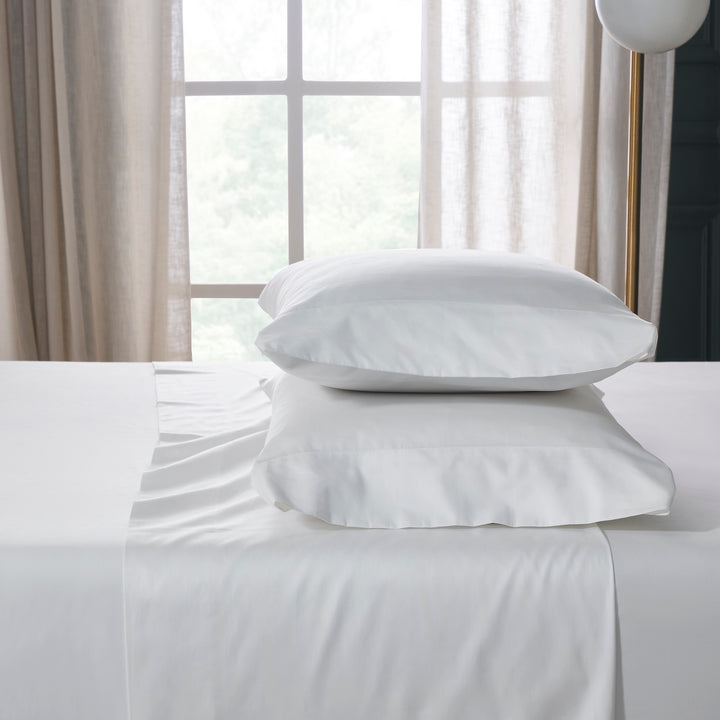 QSS-535-6080_2|Stack of pure white 100% cotton sheets and two soft pillowcases, highlighting premium, breathable bed linens.