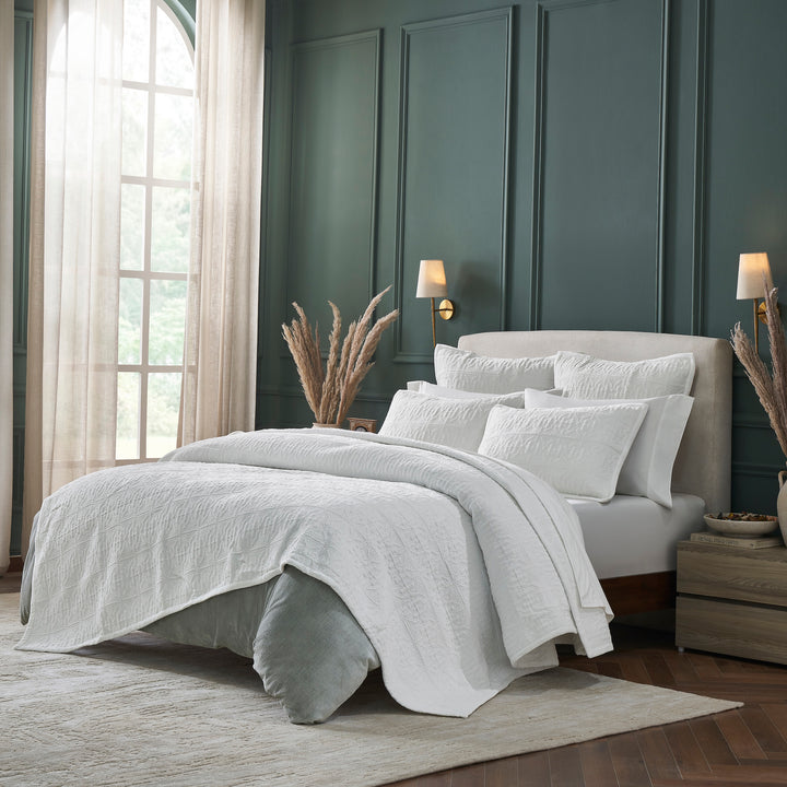 QT-376-11096_2|Crisp white patterned quilt set draped over a bed with matching shams, offering luxurious comfort and stylish bedroom appeal.